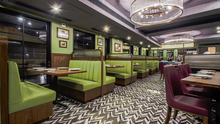 A retro-themed restaurant with green and purple booths, a tiled floor, and vintage-style lighting. 